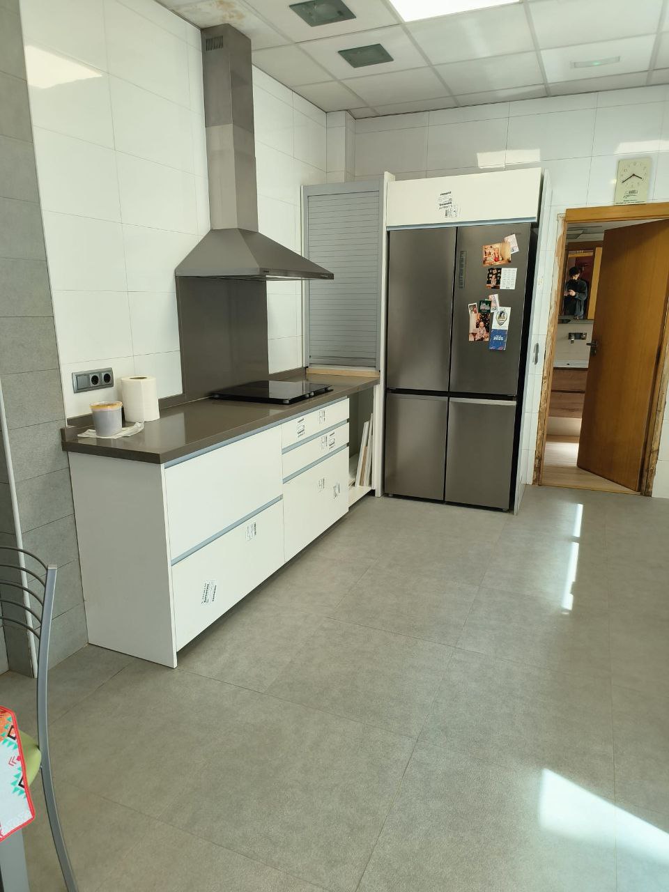 Cocina blanca, con nevera doble puerta y puerta de paso marrón