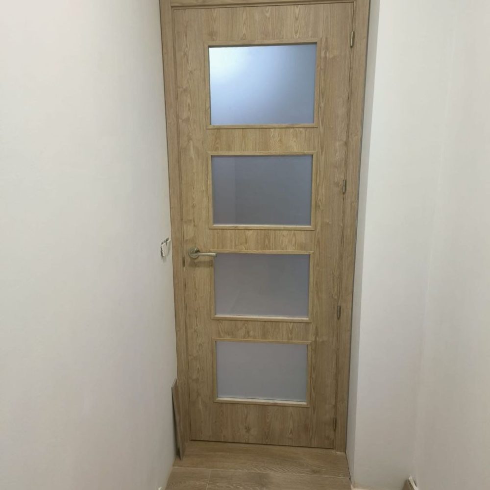 Puerta de madera acabado claro con cuatro ventanas semi translucidas